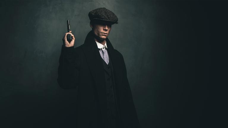 Dangerous retro 1920s English gangster standing with gun