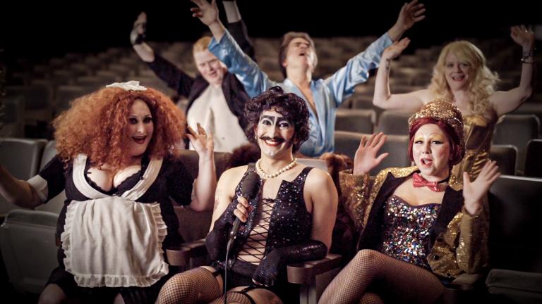 Documentary contributors sitting in theatre seating dressed up as members of the Rocky Horror cast
