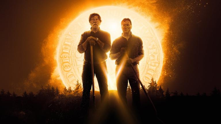 Rick and Marty Lagina hold shovels while standing in front of a glowing golden coin
